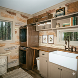 Boat-themed wallpaper with tan and brown boats by Oarshale, styled in a laundry room with a window view of a forest.
