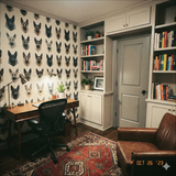 Facet shepherd wallpaper with a pattern of German shepherd heads, in front of a wooden desk and leather chair.