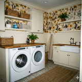 Floral and dog print wallpaper with yellow sunflowers by Sunlit Shepherd, covering a laundry room wall above white beadboard paneling.