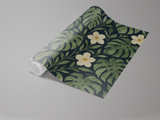 Botanical Monstera Noire Wallpaper with monstera leaf and flower pattern on a roll.