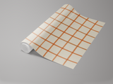 Roll of sunstone grids wallpaper with orange plaid pattern on an off-white background.